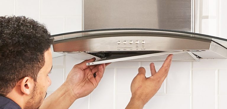 Un professionnel installe le couvercle d’une hotte de cuisinière.