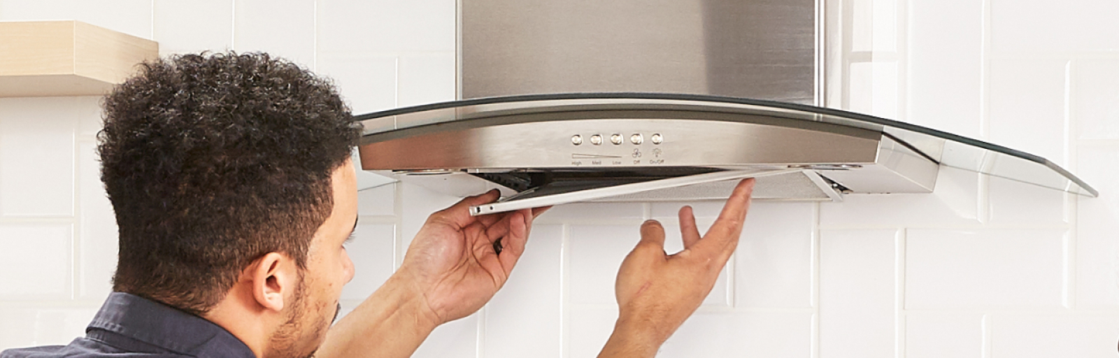 A professional installs the cover for a range hood.