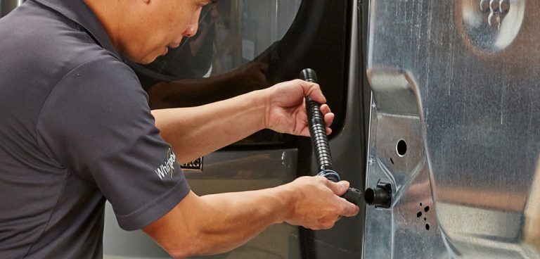 A man installs a drain hose on a washer.