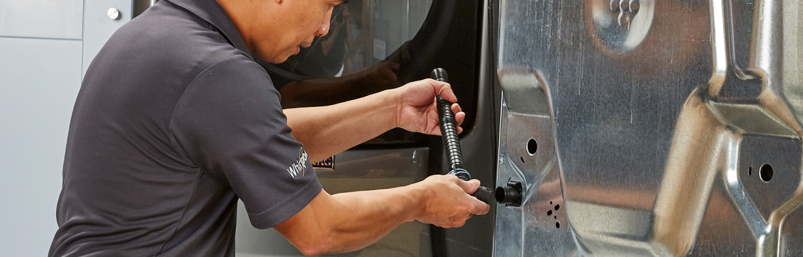 A man installs a drain hose on a washer.