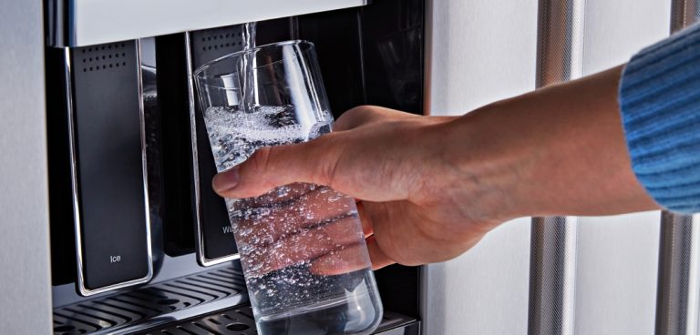Une personne remplit un verre d’eau à l’aide du distributeur d’eau externe d’un réfrigérateur.