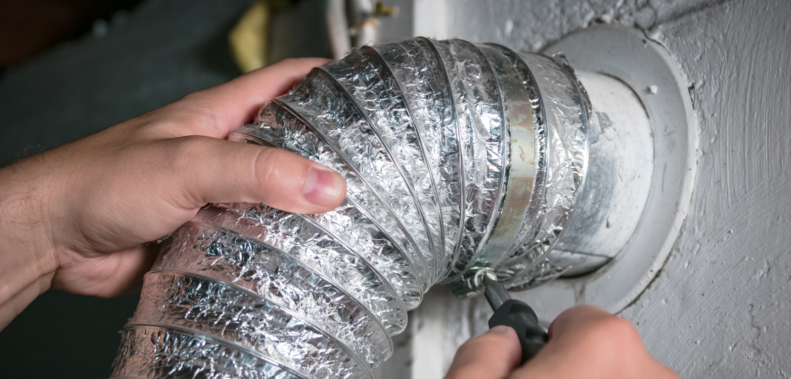 Someone installs a dryer hose with a screwdriver.