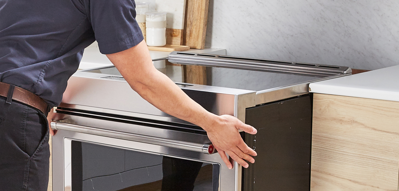 A professional pulls a range away from its installation spot.