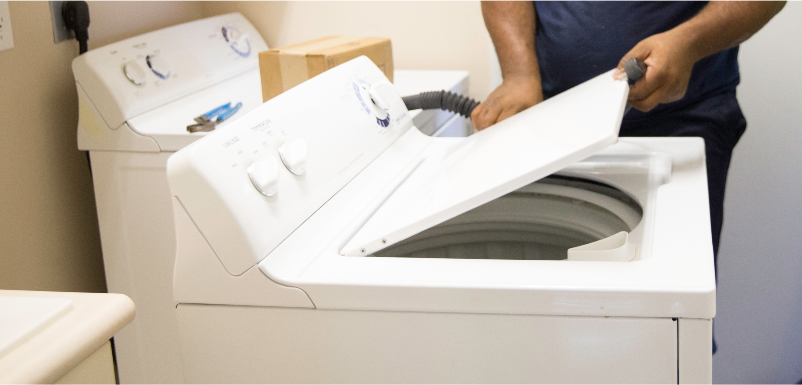 A person lifts the lid on a laundry appliance.