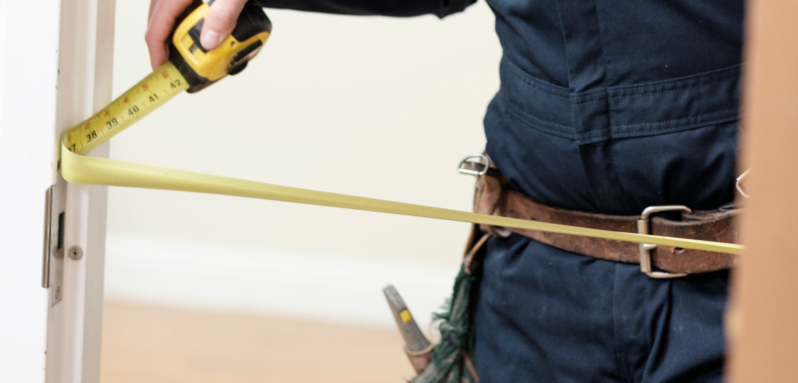 A person measures the space in a door frame.