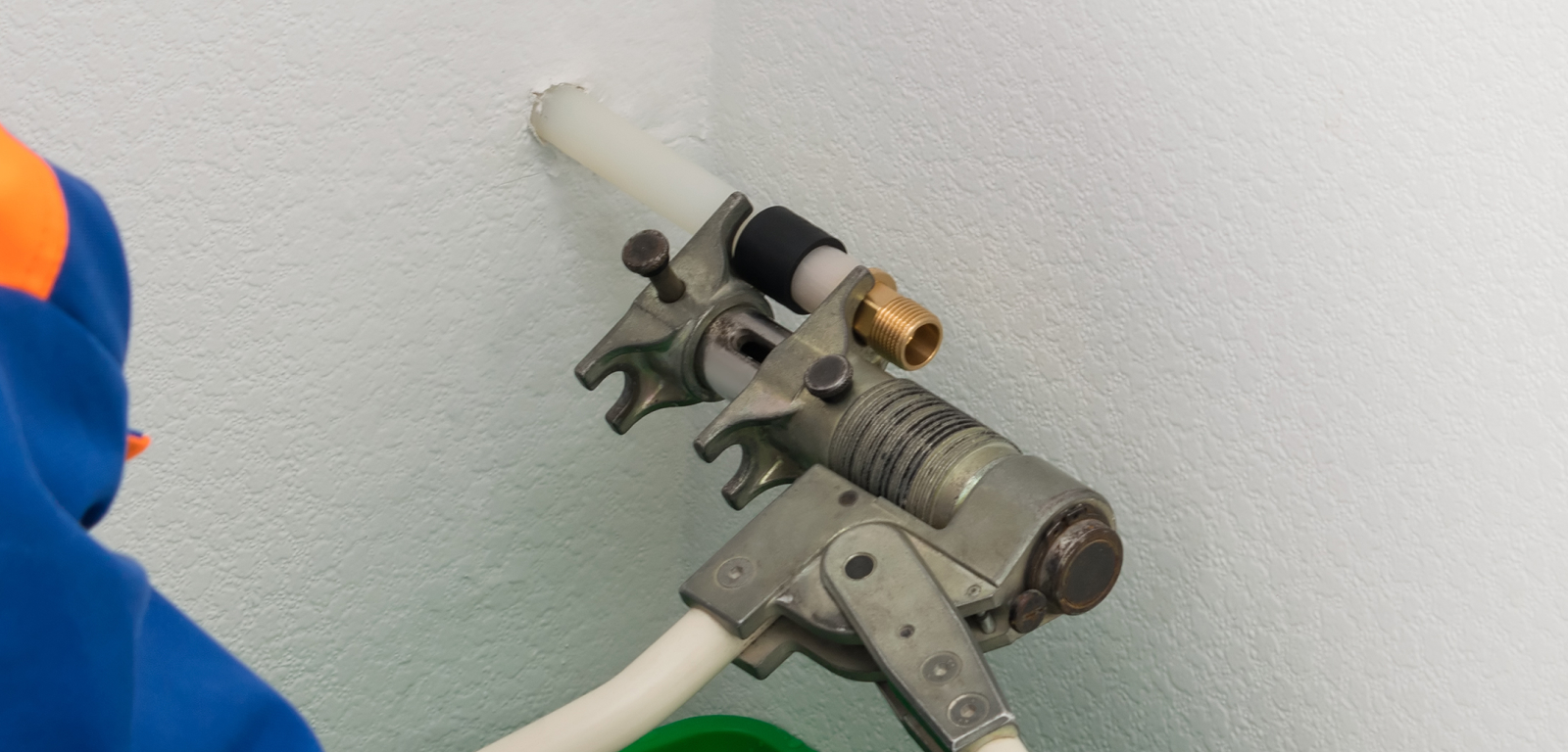 A person in front of a pipe coming out of a wall. There's a connection attached to the pipe.