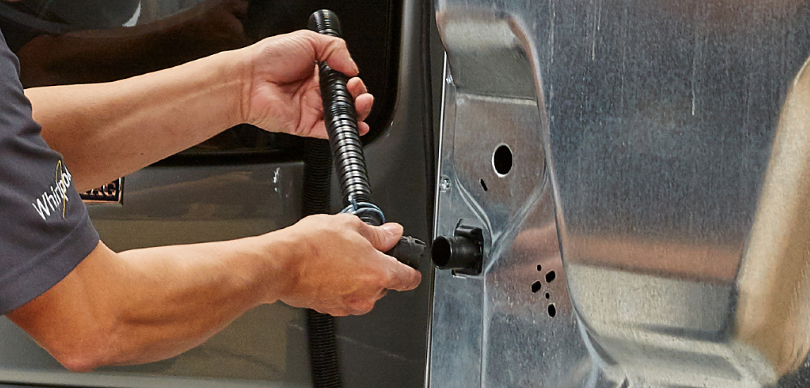 A repairperson works on the back of a washer.