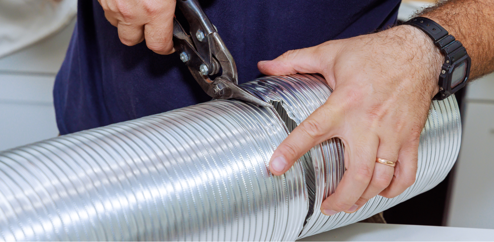 Using metal cutters, someone cuts a dryer vent.