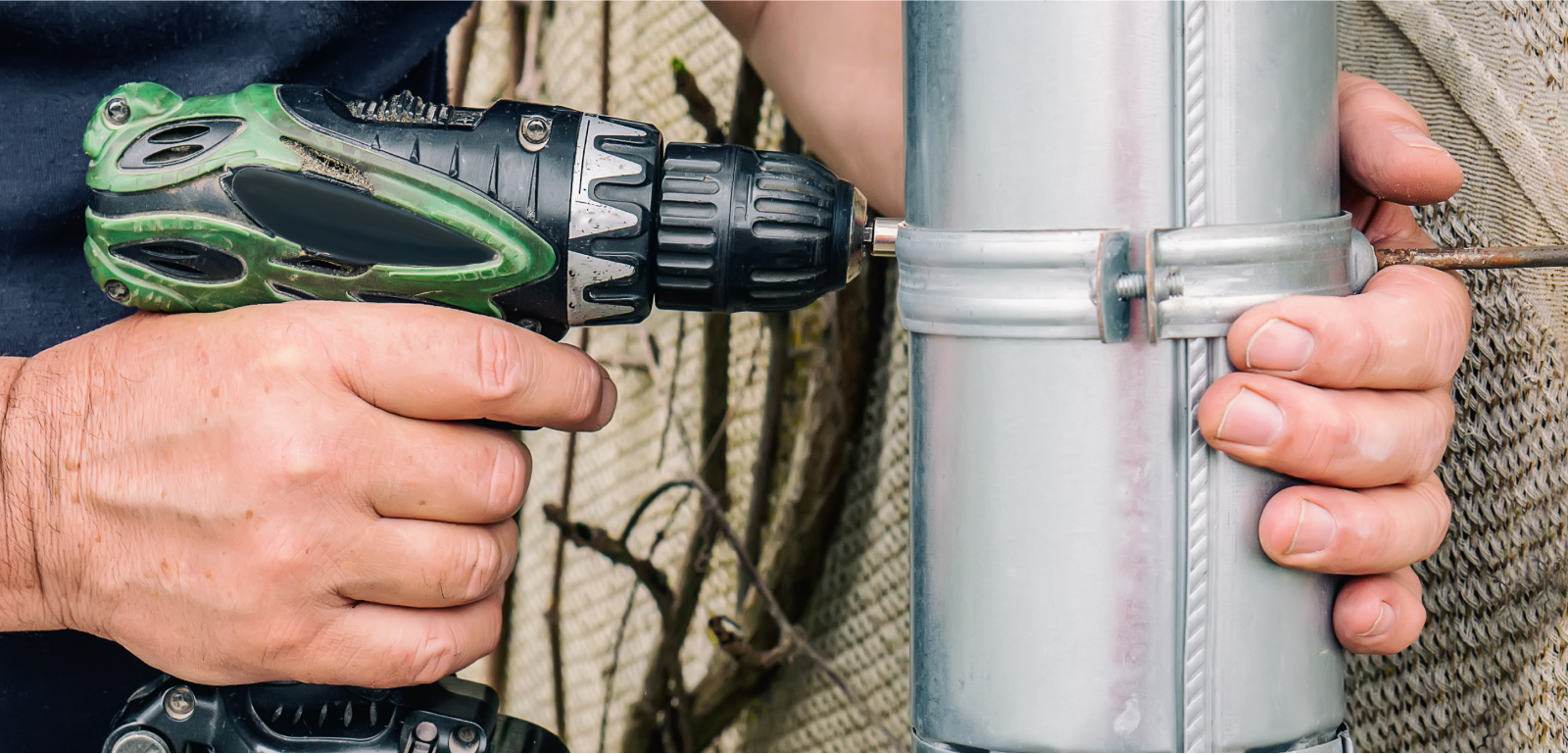 A person drills into a metal dryer vent.