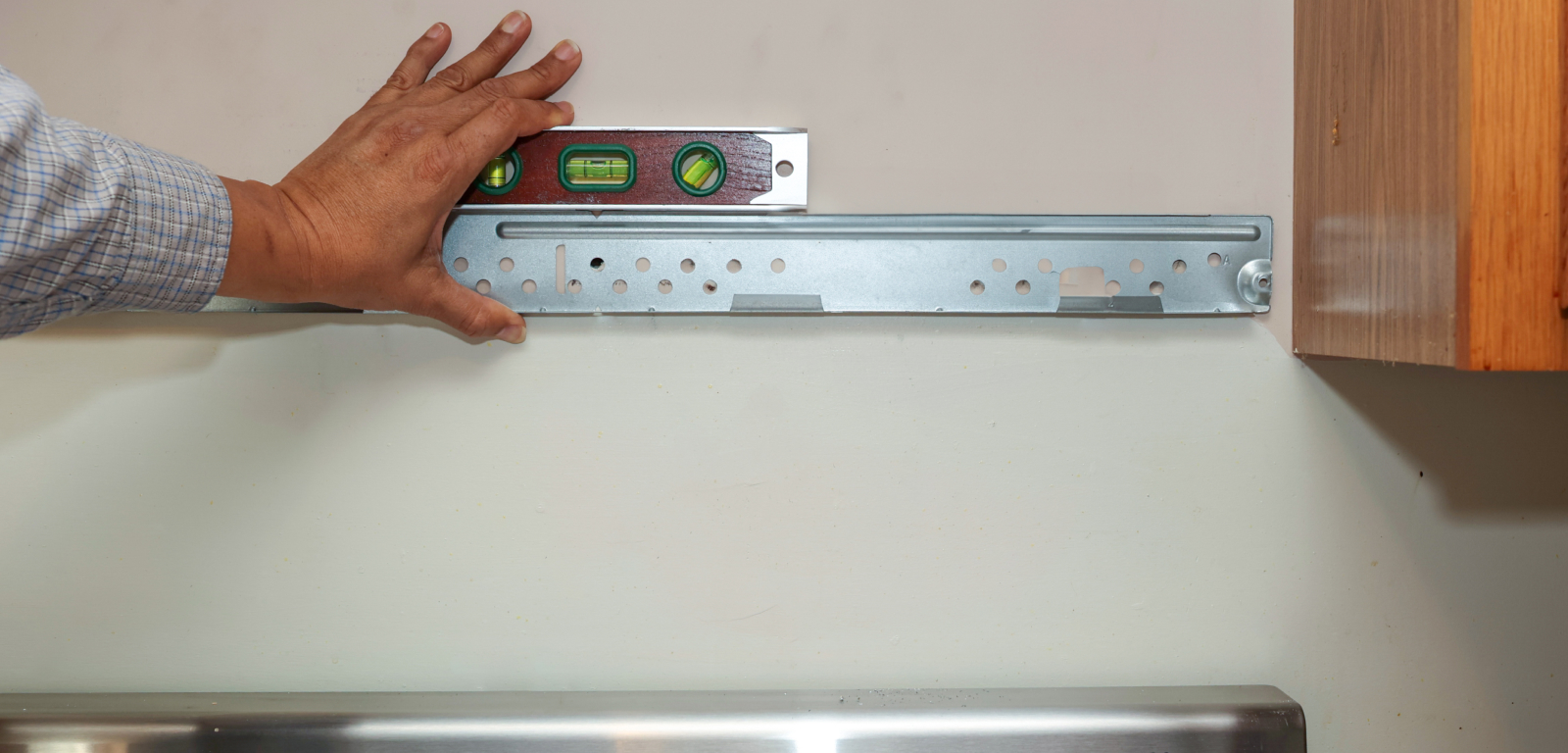 Someone holds a level against a wall to check if a metal bar is level.