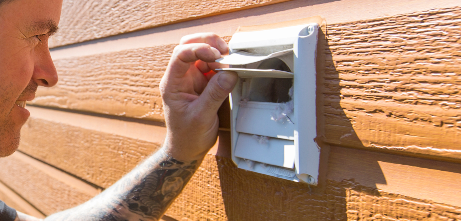 A man opens a shutter on a vent cover to inspect inside.