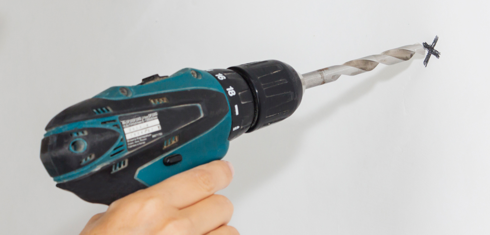 Someone drills into an "X" on the wall.