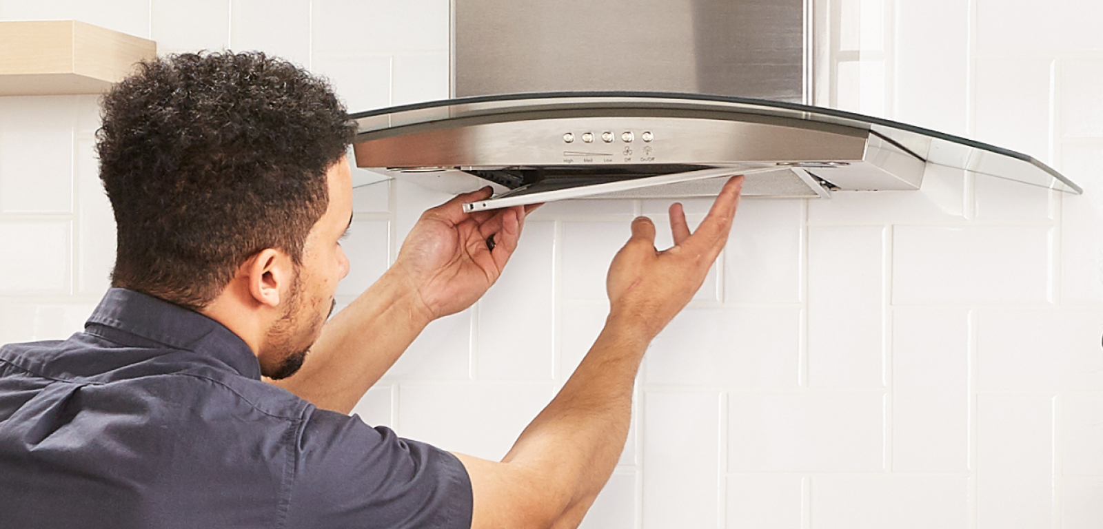 A professional installs the cover for a range hood.
