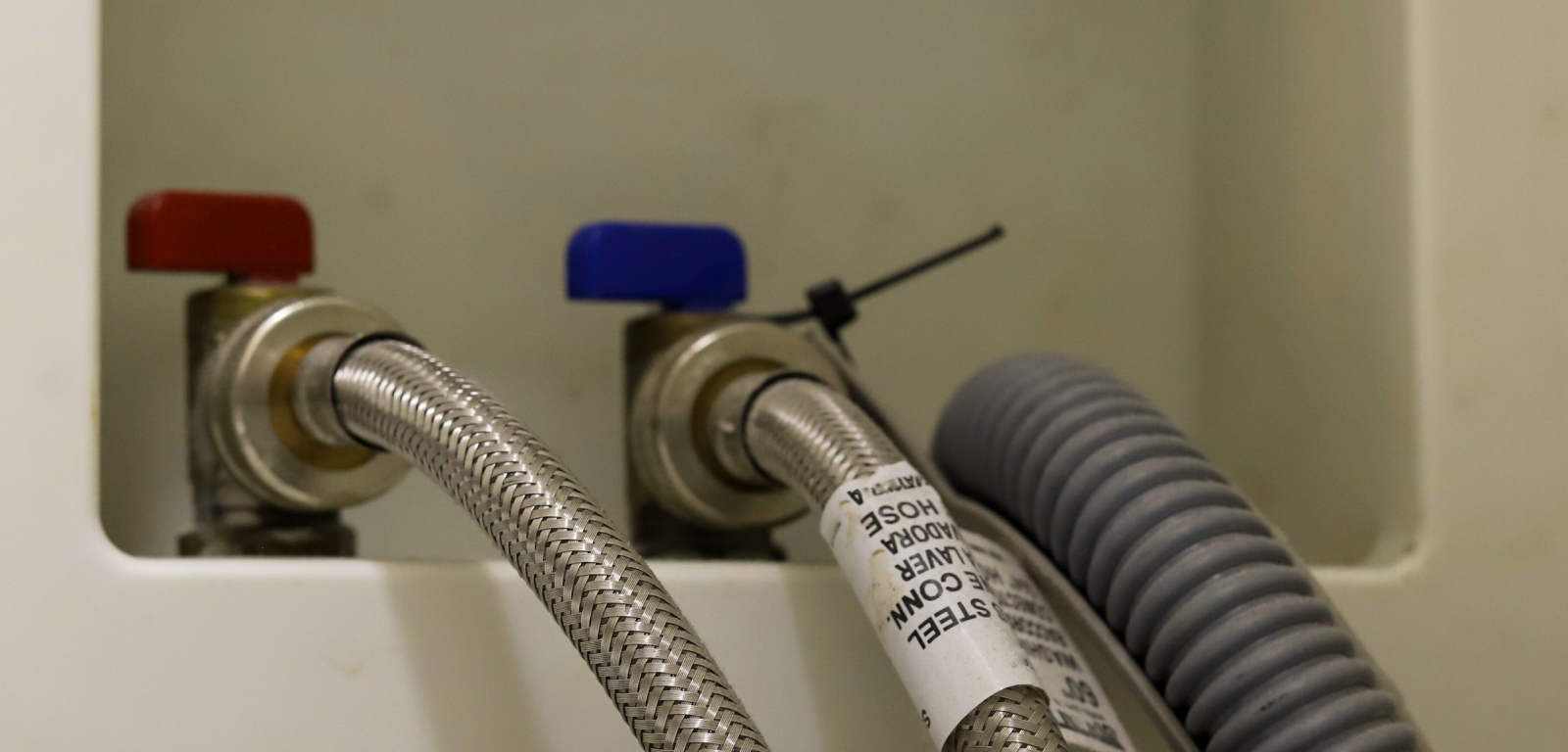 Connections for a washer. One is red for hot water and one is blue for cold water.