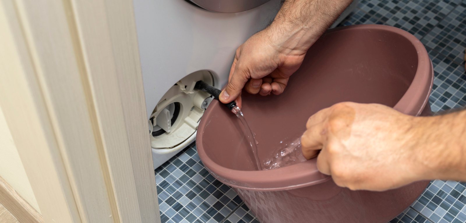 A person fills a bucket with water from a washer.