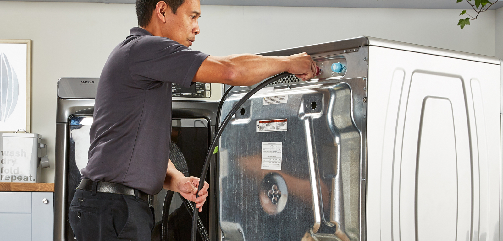 A person uninstalls a washer by removing the cord.