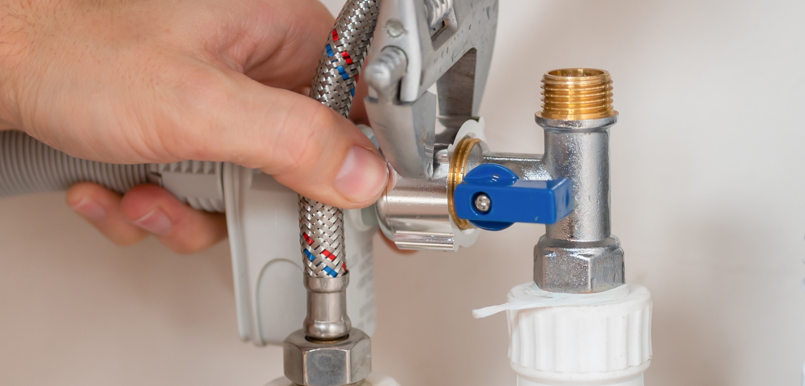 Img_Step2_1600x768 Someone uses a wrench to tighten a connection for a dishwasher.