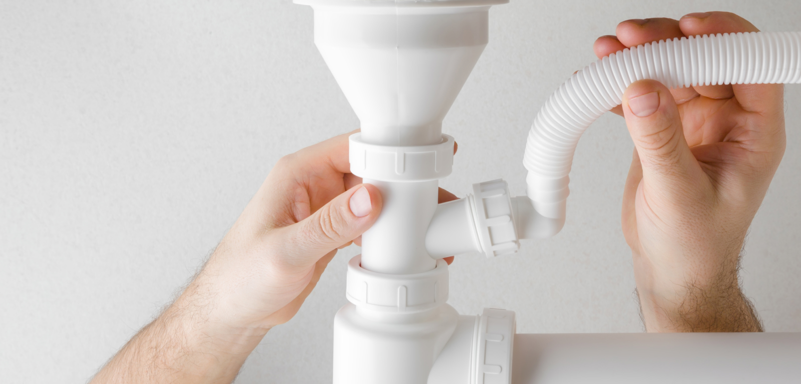 Img_Step4_1600x768 Two hands hold pipes that connect to a dishwasher.